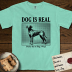 Dog is Real Vizsla T-Shirt flat lay in Island Reef, featuring Black halftone newspaper photo of a lean Vizsla with long ears standing in profile with head turned to the camera, under the headline DOG IS REAL, with the caption Praise Be to Dog. Woof..