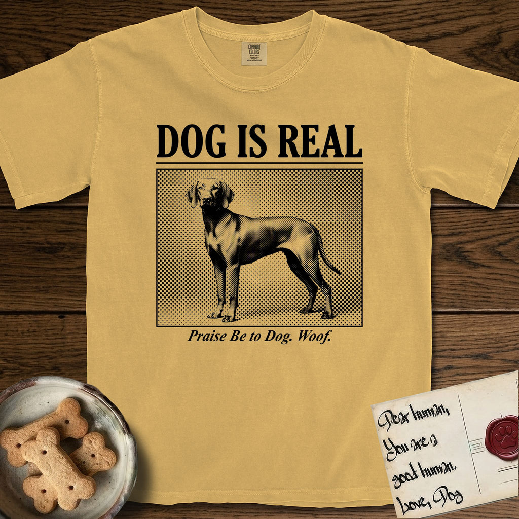 Dog is Real Vizsla T-Shirt flat lay in Mustard, featuring Black halftone newspaper photo of a lean Vizsla with long ears standing in profile with head turned to the camera, under the headline DOG IS REAL, with the caption Praise Be to Dog. Woof..
