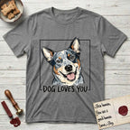 Dog Loves You Australian Cattle Dog T-Shirt flat lay in Graphite Heather, featuring Ink and watercolor portrait of a smiling blue Australian Cattle Dog with a speckled coat, tan eyebrows and upright ears, head tilted inside a black frame above hand-lettered text reading DOG LOVES YOU.