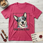 Dog Loves You Australian Cattle Dog T-Shirt flat lay in Heather Red, featuring Ink and watercolor portrait of a smiling blue Australian Cattle Dog with a speckled coat, tan eyebrows and upright ears, head tilted inside a black frame above hand-lettered text reading DOG LOVES YOU.
