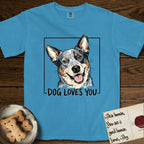 Dog Loves You Australian Cattle Dog T-Shirt flat lay in Royal Caribe, featuring Ink and watercolor portrait of a smiling blue Australian Cattle Dog with a speckled coat, tan eyebrows and upright ears, head tilted inside a black frame above hand-lettered text reading DOG LOVES YOU.
