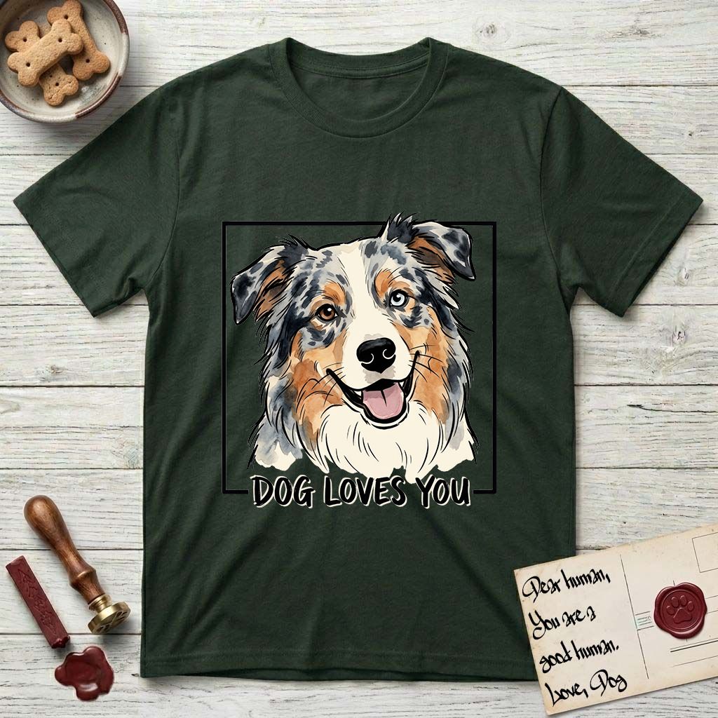 Dog Loves You Australian Shepherd T-Shirt flat lay in Forest Green, featuring Ink and watercolor portrait of a smiling blue merle Australian Shepherd with one brown eye and one blue eye and a cream blaze, head tilted inside a black frame above hand-lettered text reading DOG LOVES YOU.