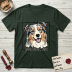 Dog Loves You Australian Shepherd T-Shirt flat lay in Forest Green, featuring Ink and watercolor portrait of a smiling blue merle Australian Shepherd with one brown eye and one blue eye and a cream blaze, head tilted inside a black frame above hand-lettered text reading DOG LOVES YOU.