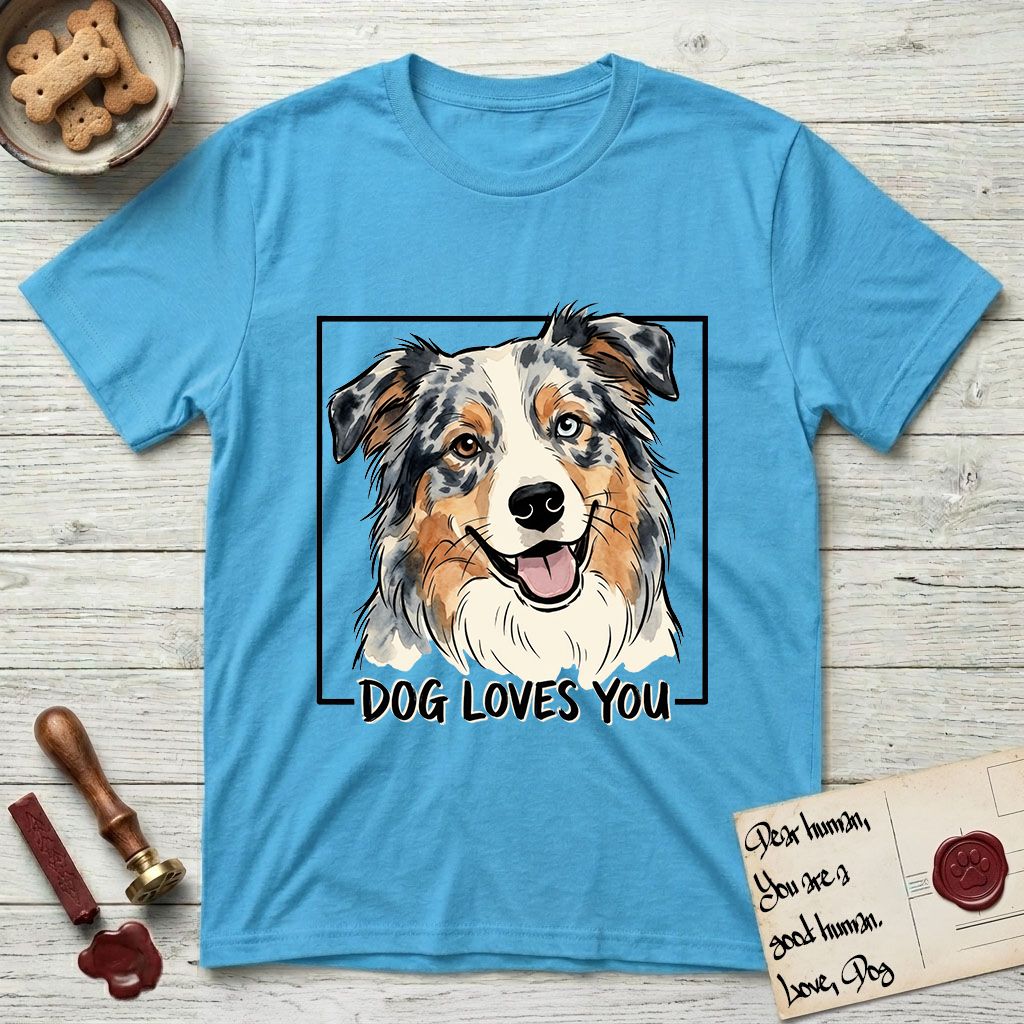 Dog Loves You Australian Shepherd T-Shirt flat lay in Sky, featuring Ink and watercolor portrait of a smiling blue merle Australian Shepherd with one brown eye and one blue eye and a cream blaze, head tilted inside a black frame above hand-lettered text reading DOG LOVES YOU.