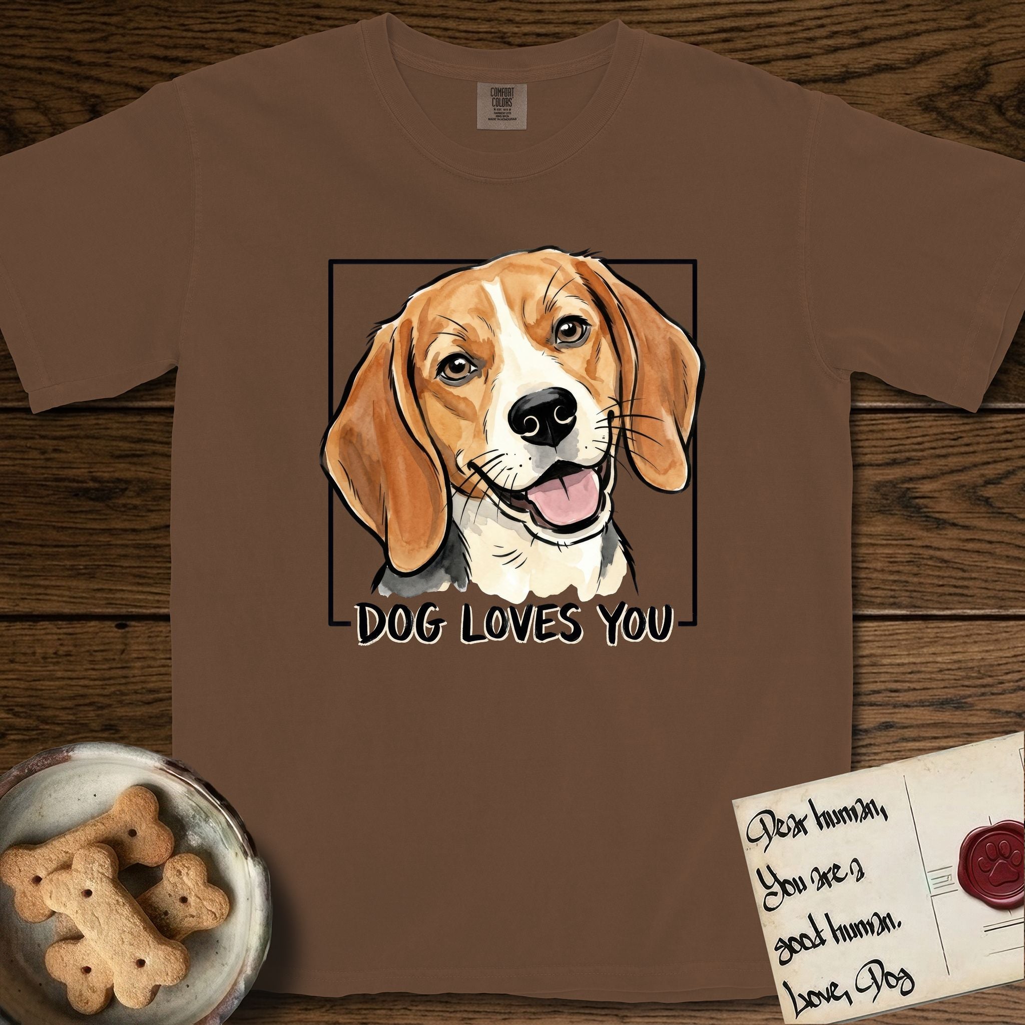 Dog Loves You Beagle T-Shirt flat lay in Espresso, featuring Ink and watercolor portrait of a smiling tricolor Beagle with long hanging ears and a cream blaze, head tilted inside a black frame above hand-lettered text reading DOG LOVES YOU.