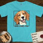 Dog Loves You Beagle T-Shirt flat lay in Lagoon Blue, featuring Ink and watercolor portrait of a smiling tricolor Beagle with long hanging ears and a cream blaze, head tilted inside a black frame above hand-lettered text reading DOG LOVES YOU.