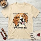 Dog Loves You Beagle T-Shirt flat lay in Natural, featuring Ink and watercolor portrait of a smiling tricolor Beagle with long hanging ears and a cream blaze, head tilted inside a black frame above hand-lettered text reading DOG LOVES YOU.
