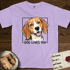 Dog Loves You Beagle T-Shirt flat lay in Orchid, featuring Ink and watercolor portrait of a smiling tricolor Beagle with long hanging ears and a cream blaze, head tilted inside a black frame above hand-lettered text reading DOG LOVES YOU.