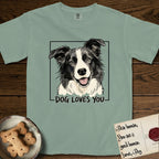 Dog Loves You Border Collie T-Shirt flat lay in Bay, featuring Ink and watercolor portrait of a smiling black and white Border Collie with a cream blaze and semi-erect ears, head tilted inside a black frame above hand-lettered text reading DOG LOVES YOU.