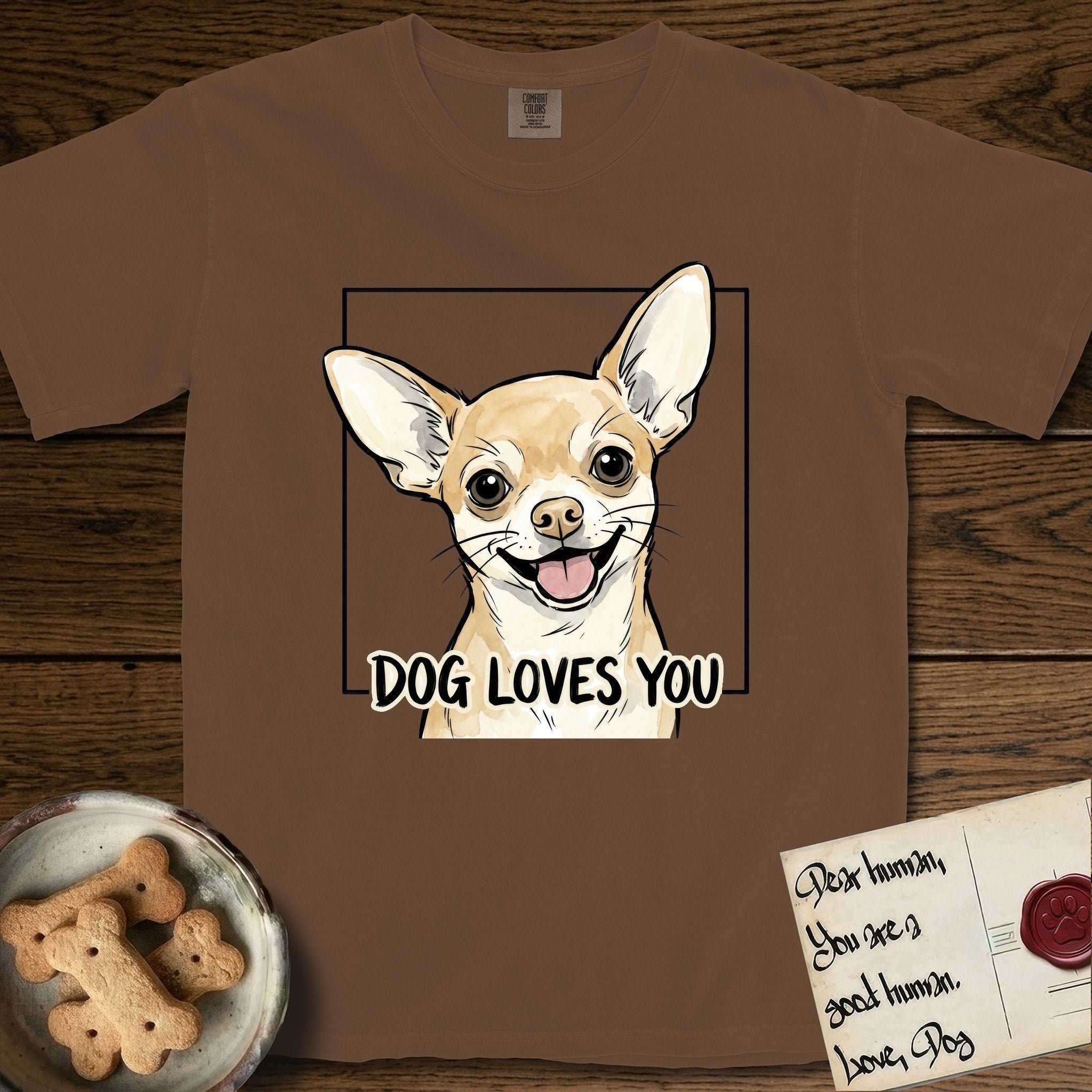 Dog Loves You Chihuahua T-Shirt flat lay in Espresso, featuring Ink and watercolor portrait of a smiling fawn Chihuahua with enormous upright bat ears and big round dark eyes, head tilted inside a black frame above hand-lettered text reading DOG LOVES YOU.