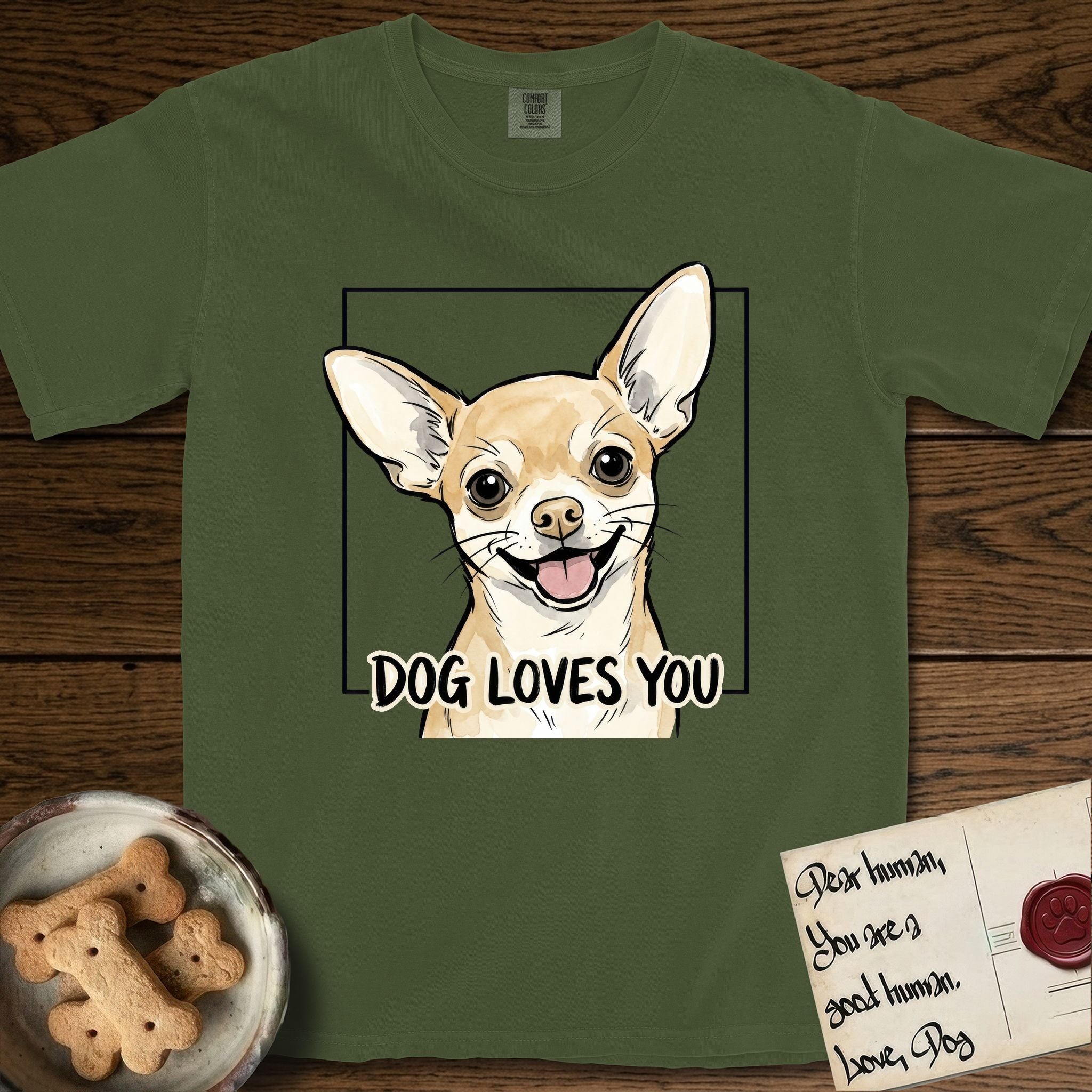Dog Loves You Chihuahua T-Shirt flat lay in Hemp, featuring Ink and watercolor portrait of a smiling fawn Chihuahua with enormous upright bat ears and big round dark eyes, head tilted inside a black frame above hand-lettered text reading DOG LOVES YOU.