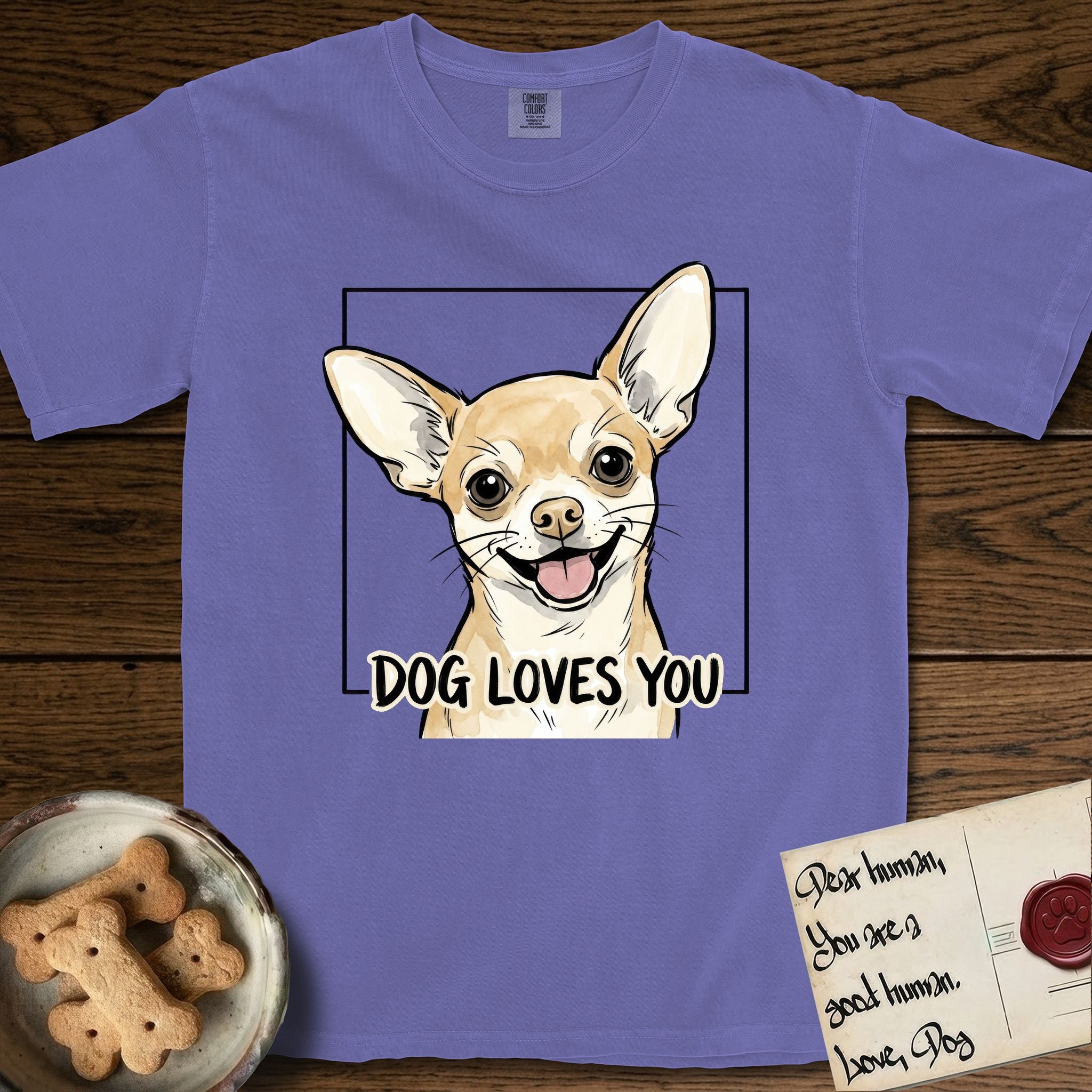 Dog Loves You Chihuahua T-Shirt flat lay in Violet, featuring Ink and watercolor portrait of a smiling fawn Chihuahua with enormous upright bat ears and big round dark eyes, head tilted inside a black frame above hand-lettered text reading DOG LOVES YOU.