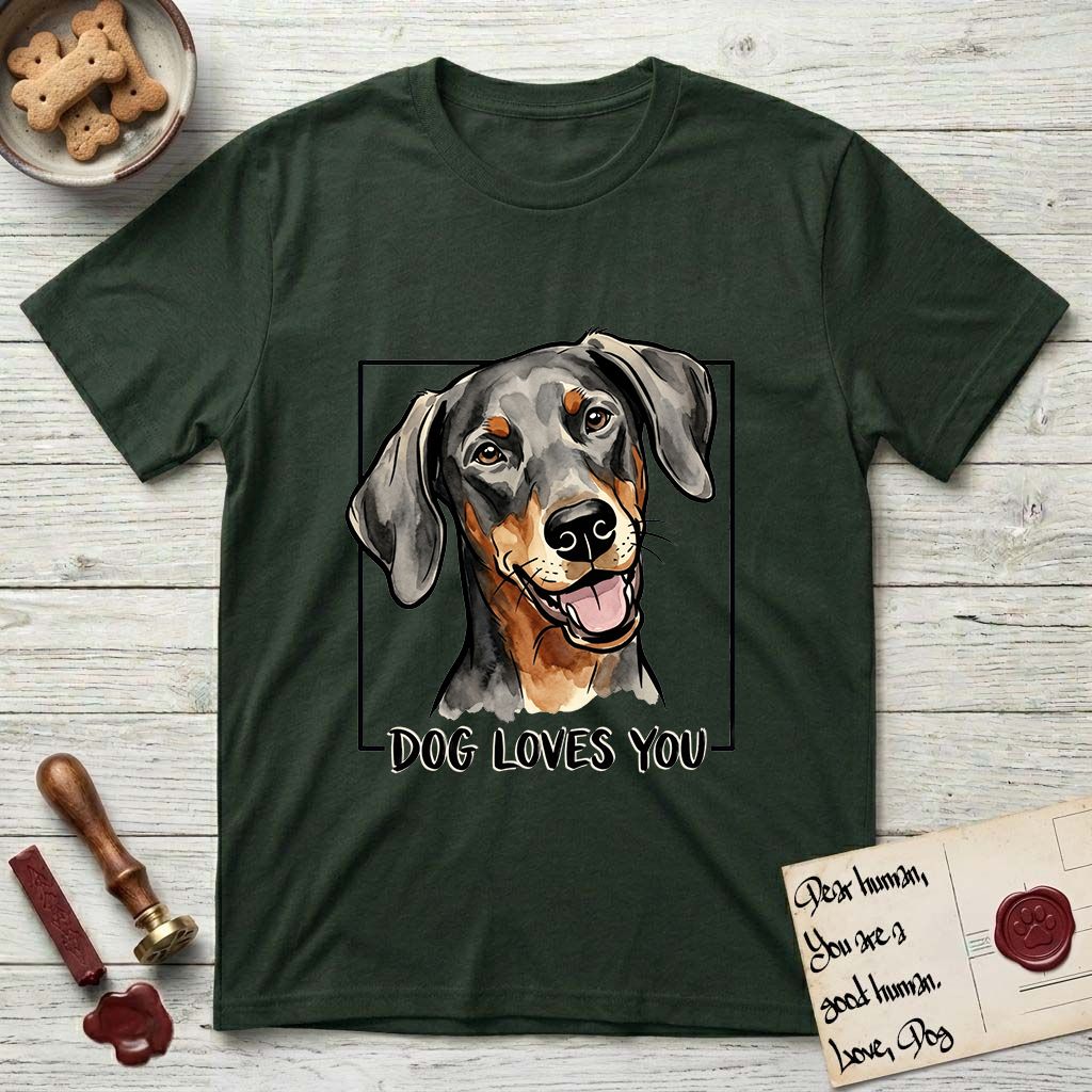 Dog Loves You Doberman T-Shirt flat lay in Forest Green, featuring Ink and watercolor portrait of a smiling black and rust Doberman with long natural hanging ears, head tilted inside a black frame above hand-lettered text reading DOG LOVES YOU.