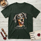 Dog Loves You Doberman T-Shirt flat lay in Forest Green, featuring Ink and watercolor portrait of a smiling black and rust Doberman with long natural hanging ears, head tilted inside a black frame above hand-lettered text reading DOG LOVES YOU.