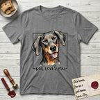 Dog Loves You Doberman T-Shirt flat lay in Graphite Heather, featuring Ink and watercolor portrait of a smiling black and rust Doberman with long natural hanging ears, head tilted inside a black frame above hand-lettered text reading DOG LOVES YOU.