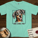 Dog Loves You Doberman T-Shirt flat lay in Island Reef, featuring Ink and watercolor portrait of a smiling black and rust Doberman with long natural hanging ears, head tilted inside a black frame above hand-lettered text reading DOG LOVES YOU.