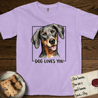 Dog Loves You Doberman T-Shirt flat lay in Orchid, featuring Ink and watercolor portrait of a smiling black and rust Doberman with long natural hanging ears, head tilted inside a black frame above hand-lettered text reading DOG LOVES YOU.