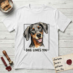 Dog Loves You Doberman T-Shirt flat lay in White, featuring Ink and watercolor portrait of a smiling black and rust Doberman with long natural hanging ears, head tilted inside a black frame above hand-lettered text reading DOG LOVES YOU.