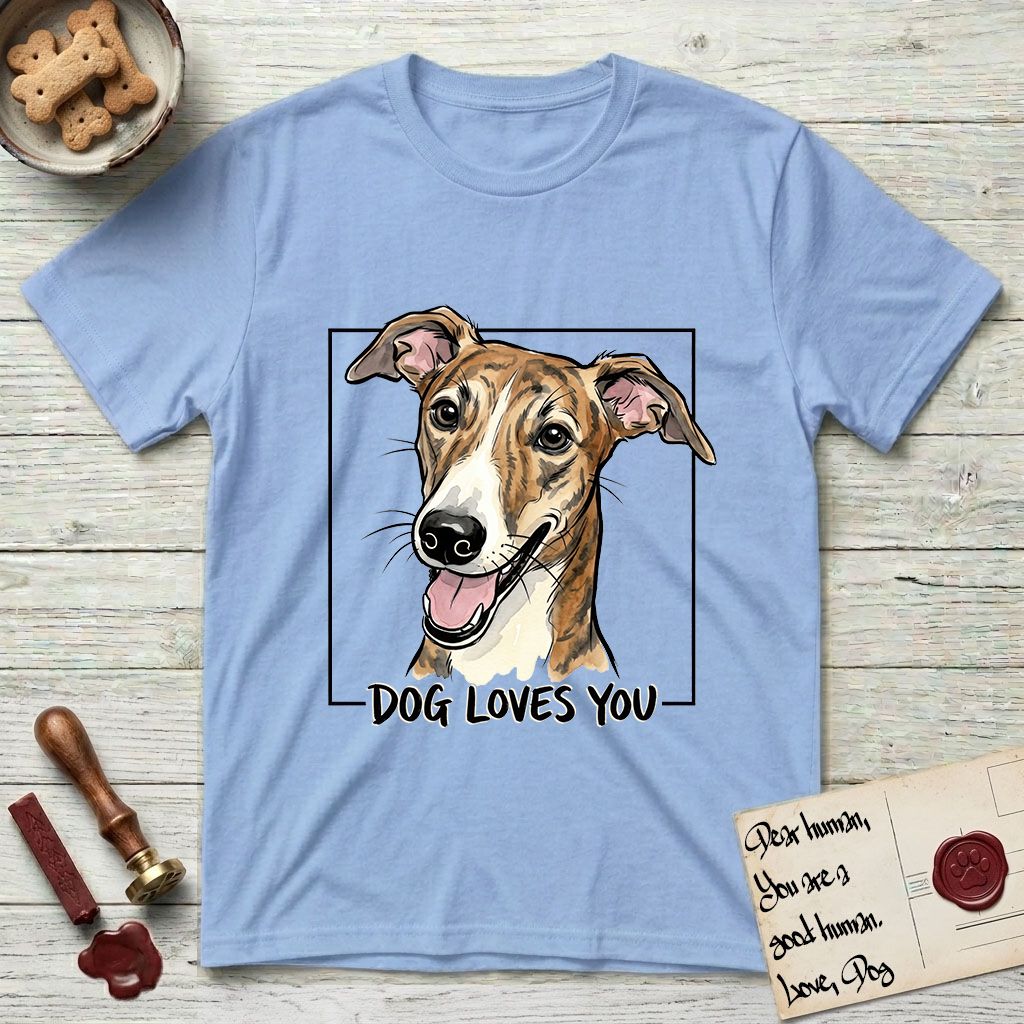 Dog Loves You Galgo T-Shirt flat lay in Light Blue, featuring Ink and watercolor portrait of a smiling brindle Galgo with a long narrow muzzle and folded rose ears, head tilted inside a black frame above hand-lettered text reading DOG LOVES YOU.