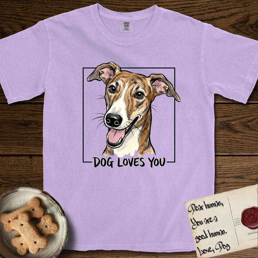 Dog Loves You Galgo T-Shirt flat lay in Orchid, featuring Ink and watercolor portrait of a smiling brindle Galgo with a long narrow muzzle and folded rose ears, head tilted inside a black frame above hand-lettered text reading DOG LOVES YOU.