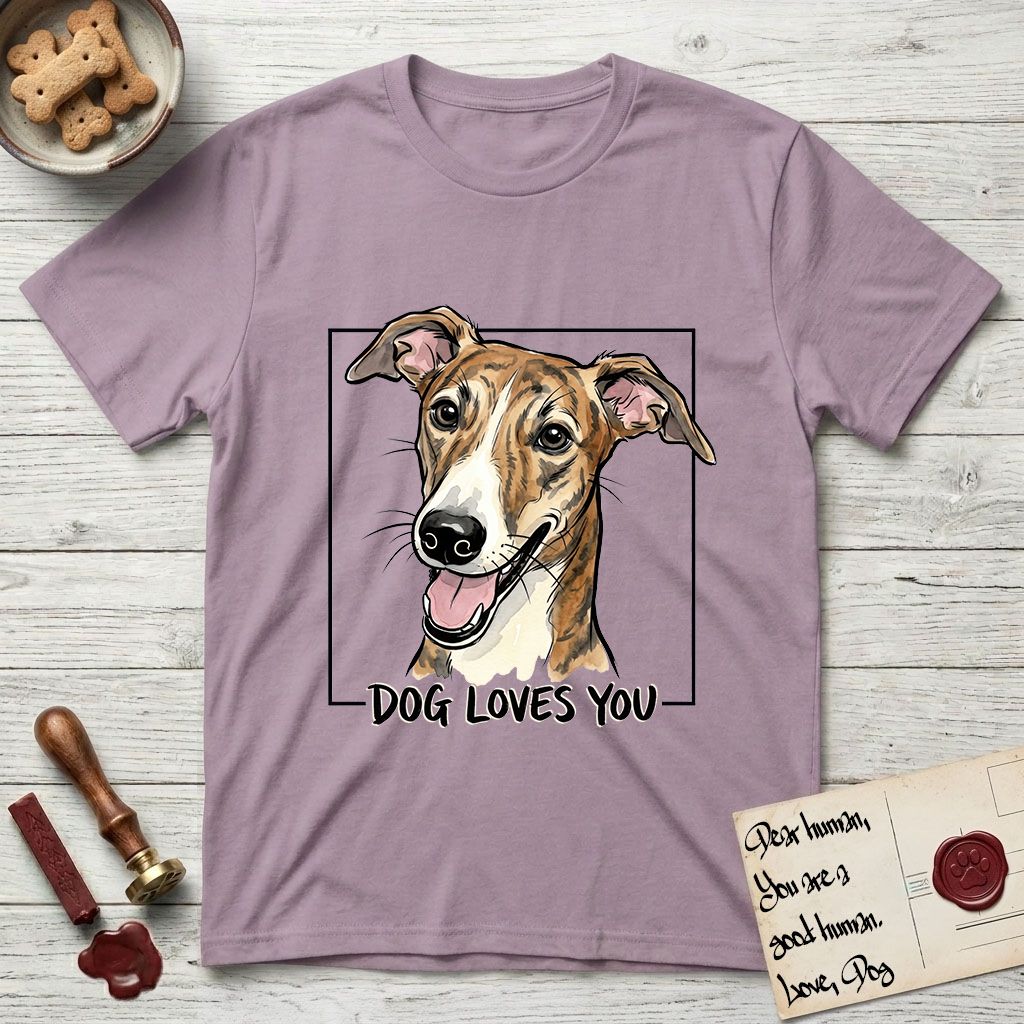 Dog Loves You Galgo T-Shirt flat lay in Paragon, featuring Ink and watercolor portrait of a smiling brindle Galgo with a long narrow muzzle and folded rose ears, head tilted inside a black frame above hand-lettered text reading DOG LOVES YOU.