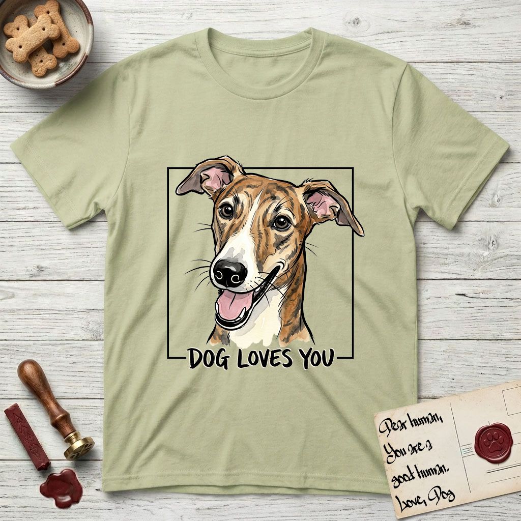 Dog Loves You Galgo T-Shirt flat lay in Pistachio, featuring Ink and watercolor portrait of a smiling brindle Galgo with a long narrow muzzle and folded rose ears, head tilted inside a black frame above hand-lettered text reading DOG LOVES YOU.