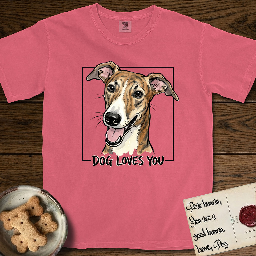 Dog Loves You Galgo T-Shirt flat lay in Watermelon, featuring Ink and watercolor portrait of a smiling brindle Galgo with a long narrow muzzle and folded rose ears, head tilted inside a black frame above hand-lettered text reading DOG LOVES YOU.