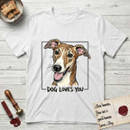 Dog Loves You Galgo T-Shirt flat lay in White, featuring Ink and watercolor portrait of a smiling brindle Galgo with a long narrow muzzle and folded rose ears, head tilted inside a black frame above hand-lettered text reading DOG LOVES YOU.