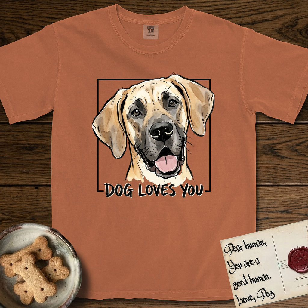 Dog Loves You Great Dane T-Shirt flat lay in Yam, featuring Ink and watercolor portrait of a smiling fawn Great Dane with a black mask and natural floppy ears, head tilted inside a black frame above hand-lettered text reading DOG LOVES YOU.