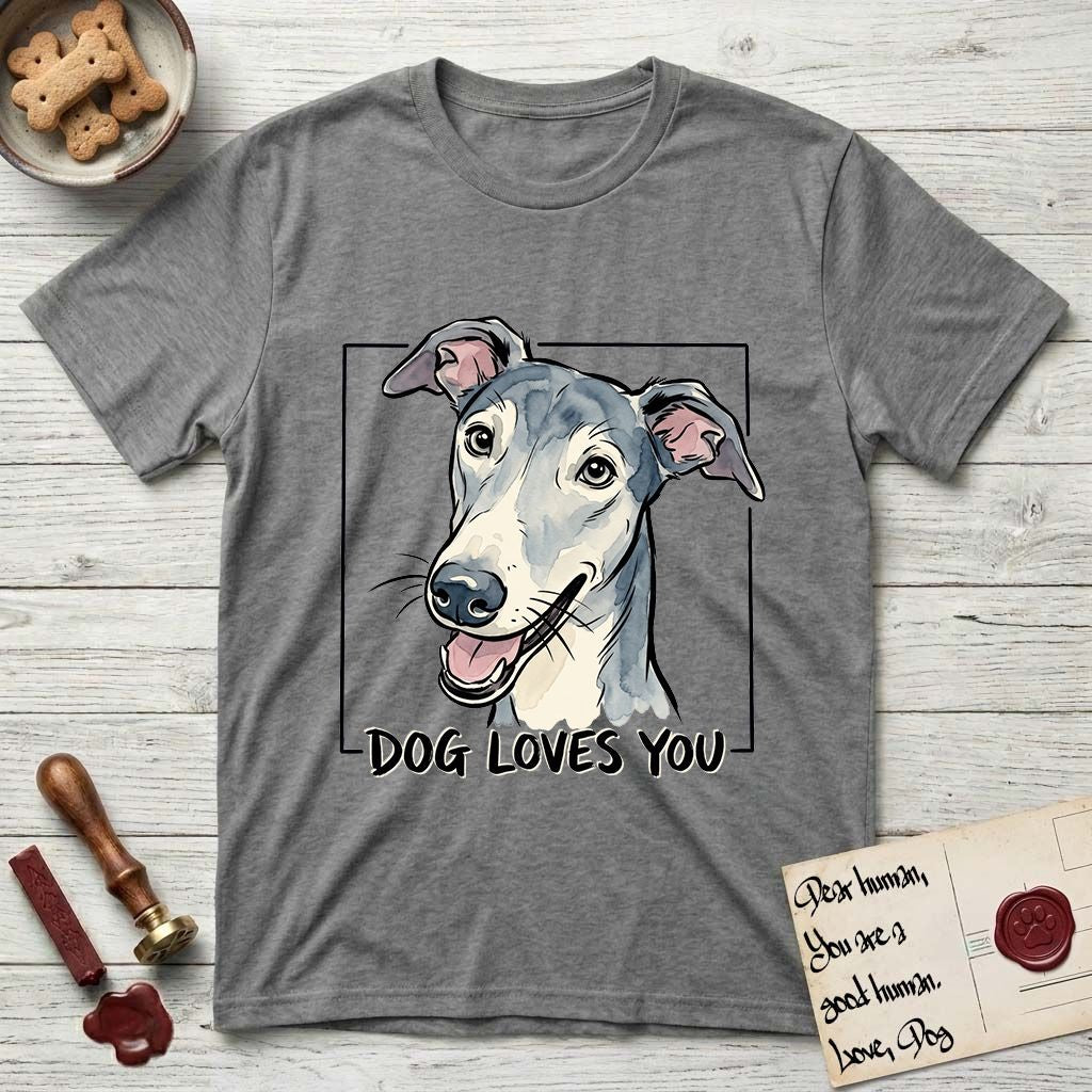 Dog Loves You Greyhound T-Shirt flat lay in Graphite Heather, featuring Ink and watercolor portrait of a smiling slate blue Greyhound with a long narrow muzzle, cream blaze and folded rose ears, head tilted inside a black frame above hand-lettered text reading DOG LOVES YOU.