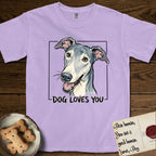 Dog Loves You Greyhound T-Shirt flat lay in Orchid, featuring Ink and watercolor portrait of a smiling slate blue Greyhound with a long narrow muzzle, cream blaze and folded rose ears, head tilted inside a black frame above hand-lettered text reading DOG LOVES YOU.