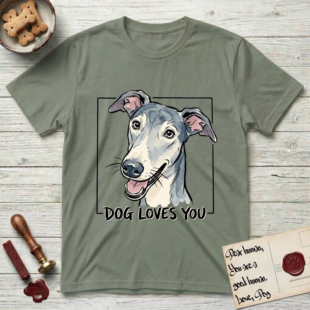 Dog Loves You Greyhound T-Shirt flat lay in Sage, featuring Ink and watercolor portrait of a smiling slate blue Greyhound with a long narrow muzzle, cream blaze and folded rose ears, head tilted inside a black frame above hand-lettered text reading DOG LOVES YOU.