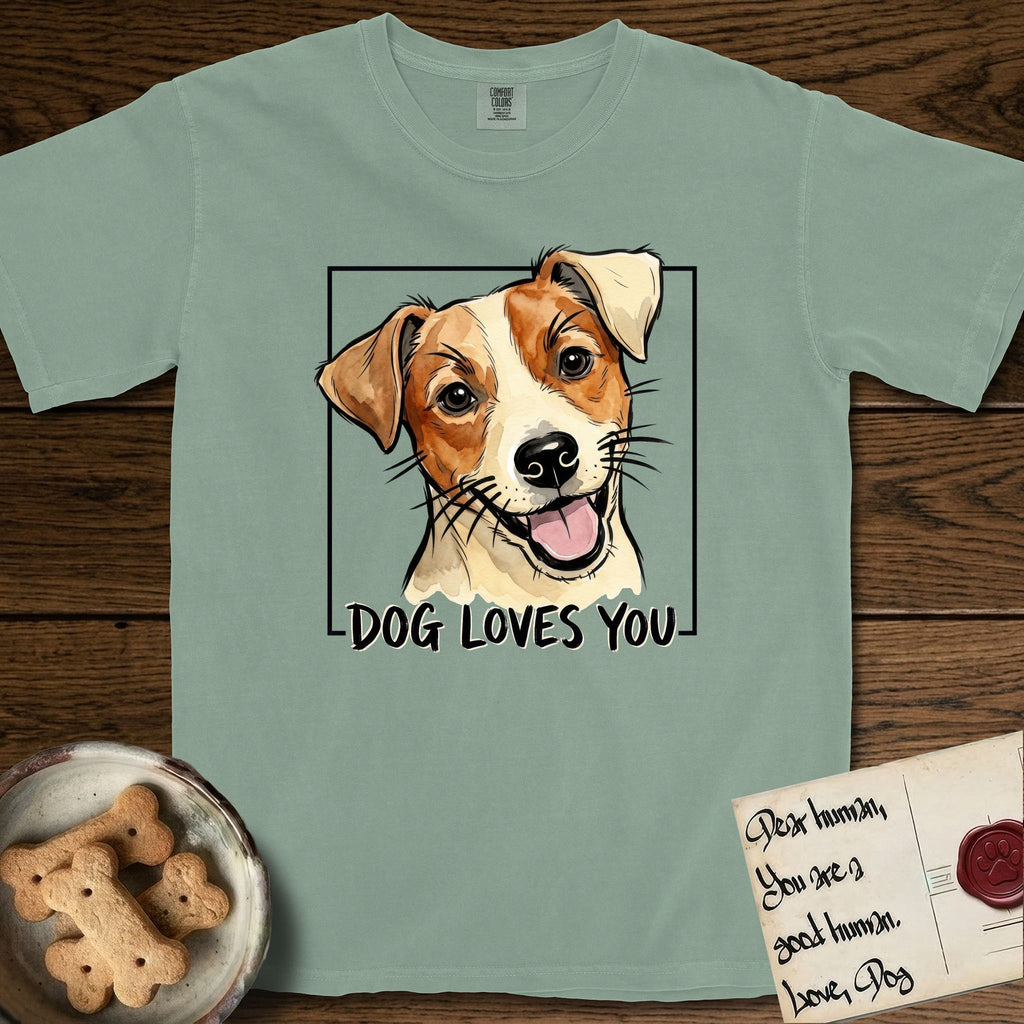 Dog Loves You Jack Russell T-Shirt flat lay in Bay, featuring Ink and watercolor portrait of a smiling cream and rust Jack Russell with folded button ears and keen dark eyes, head tilted inside a black frame above hand-lettered text reading DOG LOVES YOU.