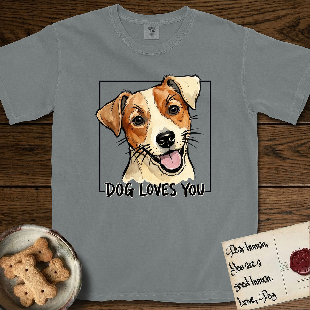 Dog Loves You Jack Russell T-Shirt flat lay in Granite, featuring Ink and watercolor portrait of a smiling cream and rust Jack Russell with folded button ears and keen dark eyes, head tilted inside a black frame above hand-lettered text reading DOG LOVES YOU.