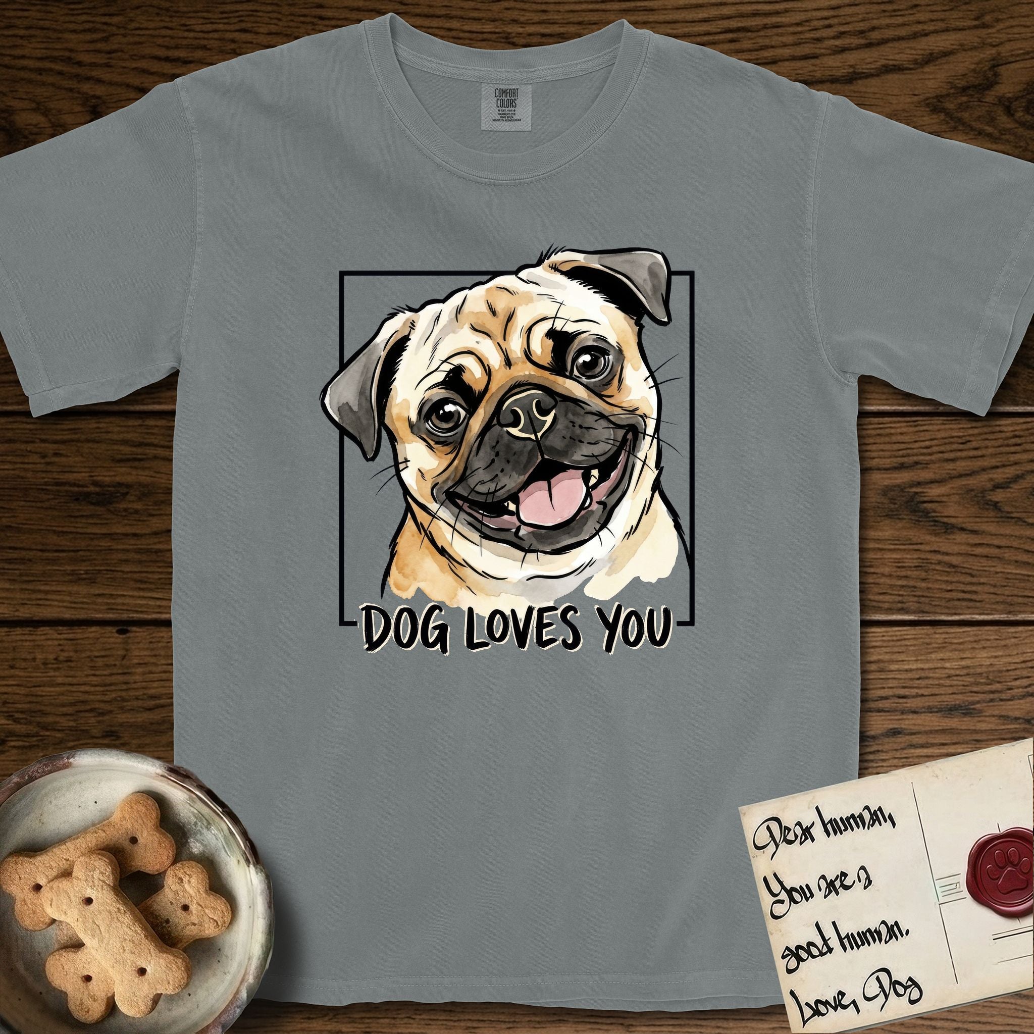 Dog Loves You Pug T-Shirt flat lay in Granite, featuring Ink and watercolor portrait of a smiling fawn Pug with a black mask, deep brow wrinkles and big round eyes, head tilted inside a black frame above hand-lettered text reading DOG LOVES YOU.