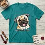 Dog Loves You Pug T-Shirt flat lay in Jade Dome, featuring Ink and watercolor portrait of a smiling fawn Pug with a black mask, deep brow wrinkles and big round eyes, head tilted inside a black frame above hand-lettered text reading DOG LOVES YOU.