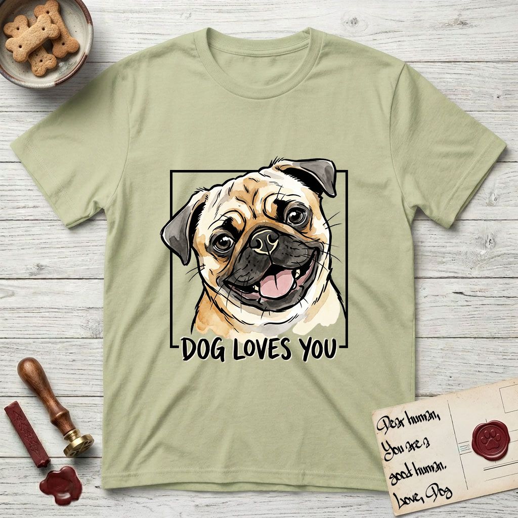 Dog Loves You Pug T-Shirt flat lay in Pistachio, featuring Ink and watercolor portrait of a smiling fawn Pug with a black mask, deep brow wrinkles and big round eyes, head tilted inside a black frame above hand-lettered text reading DOG LOVES YOU.