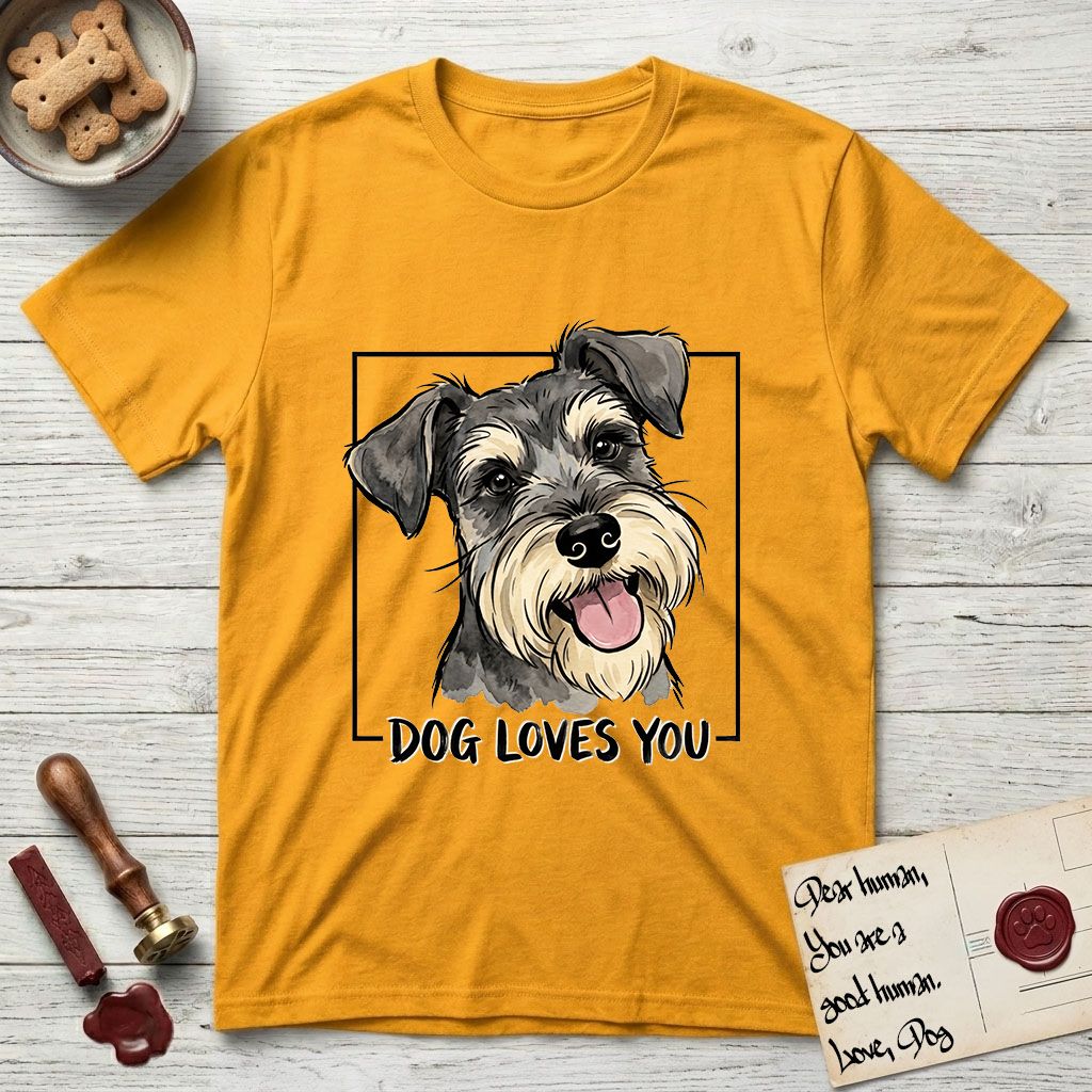 Dog Loves You Schnauzer T-Shirt flat lay in Gold, featuring Ink and watercolor portrait of a smiling salt and pepper Schnauzer with a long beard and bushy eyebrows, head tilted inside a black frame above hand-lettered text reading DOG LOVES YOU.