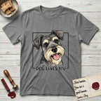 Dog Loves You Schnauzer T-Shirt flat lay in Graphite Heather, featuring Ink and watercolor portrait of a smiling salt and pepper Schnauzer with a long beard and bushy eyebrows, head tilted inside a black frame above hand-lettered text reading DOG LOVES YOU.