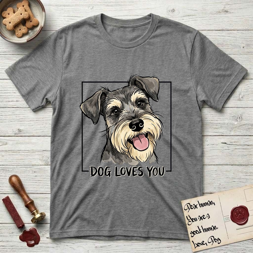 Dog Loves You Schnauzer T-Shirt flat lay in Graphite Heather, featuring Ink and watercolor portrait of a smiling salt and pepper Schnauzer with a long beard and bushy eyebrows, head tilted inside a black frame above hand-lettered text reading DOG LOVES YOU.
