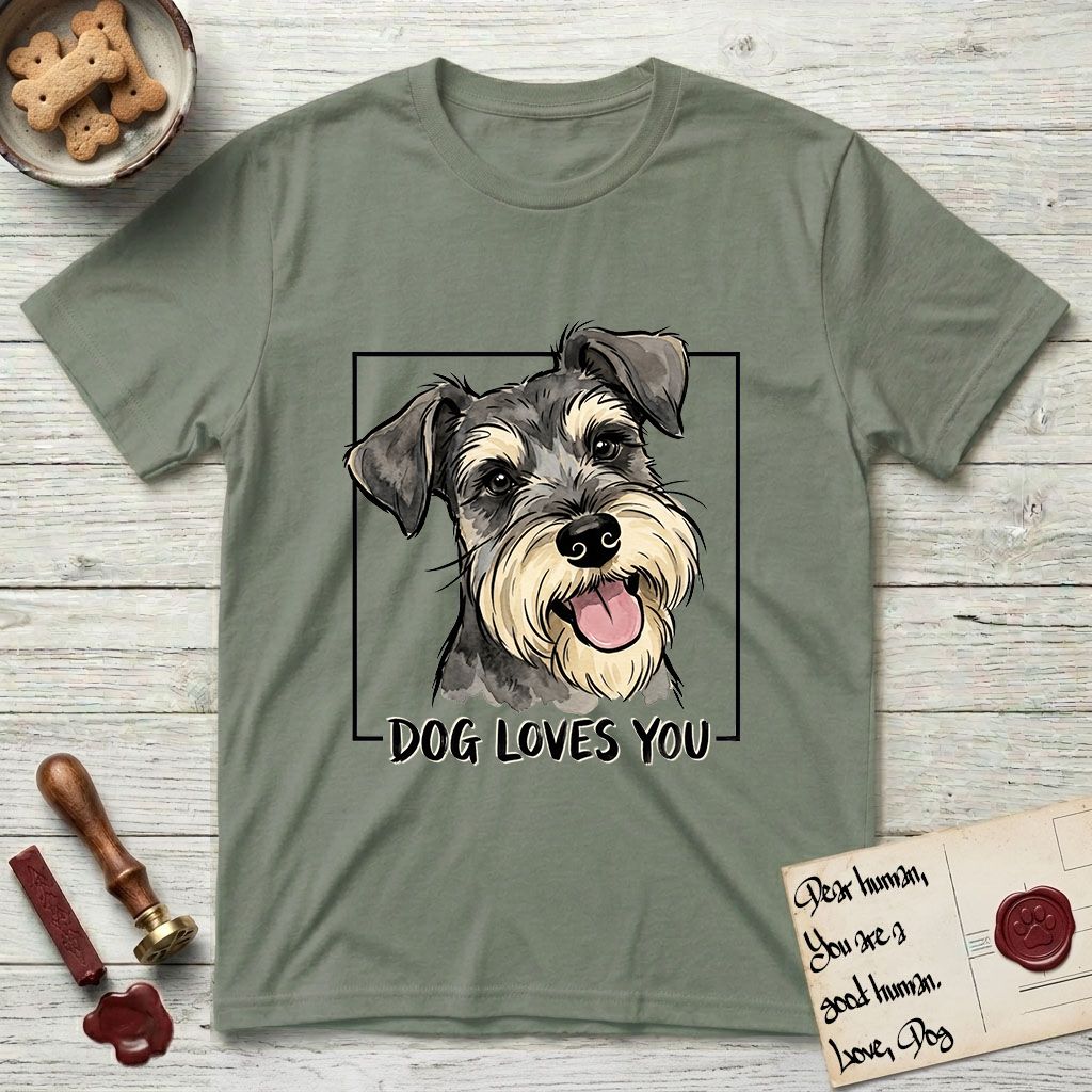 Dog Loves You Schnauzer T-Shirt flat lay in Sage, featuring Ink and watercolor portrait of a smiling salt and pepper Schnauzer with a long beard and bushy eyebrows, head tilted inside a black frame above hand-lettered text reading DOG LOVES YOU.