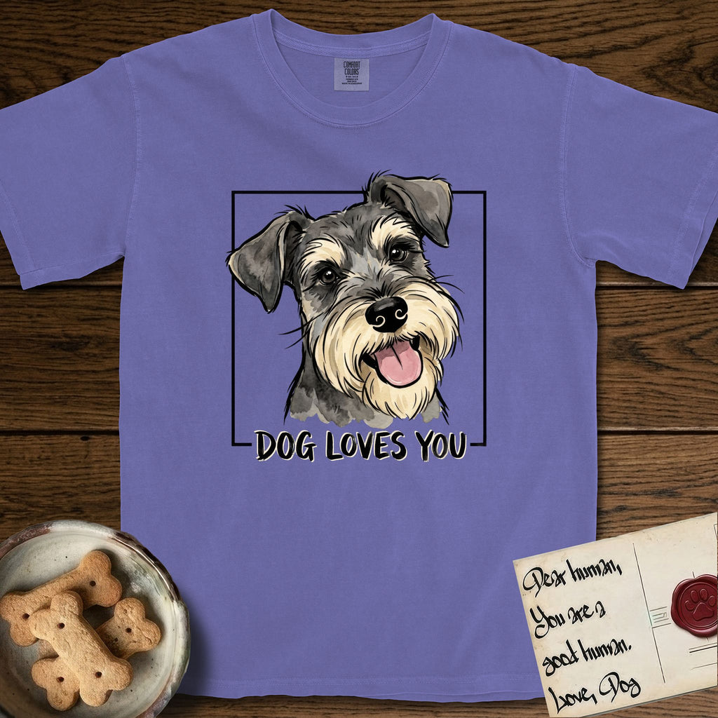Dog Loves You Schnauzer T-Shirt flat lay in Violet, featuring Ink and watercolor portrait of a smiling salt and pepper Schnauzer with a long beard and bushy eyebrows, head tilted inside a black frame above hand-lettered text reading DOG LOVES YOU.