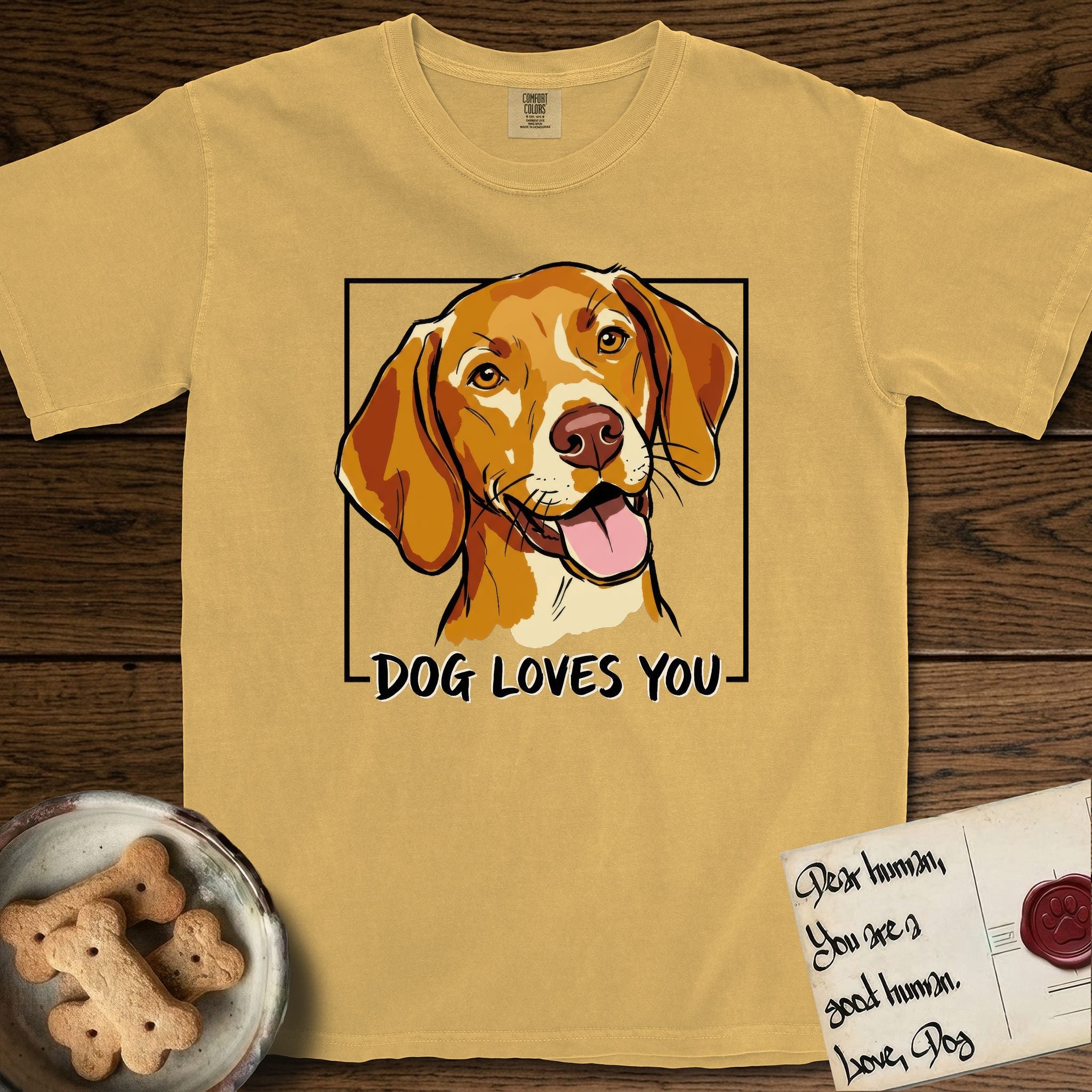 Dog Loves You Vizsla T-Shirt flat lay in Mustard, featuring Ink and watercolor portrait of a smiling golden rust Vizsla with long silky hanging ears and amber eyes, head tilted inside a black frame above hand-lettered text reading DOG LOVES YOU.
