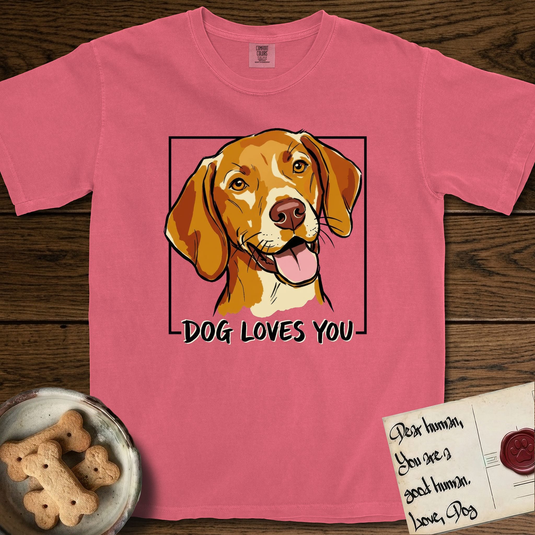 Dog Loves You Vizsla T-Shirt flat lay in Watermelon, featuring Ink and watercolor portrait of a smiling golden rust Vizsla with long silky hanging ears and amber eyes, head tilted inside a black frame above hand-lettered text reading DOG LOVES YOU.