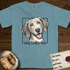 Dog Loves You Weimaraner T-Shirt flat lay in Ice Blue, featuring Ink and watercolor portrait of a smiling silver grey Weimaraner with long velvet hanging ears and pale amber eyes, head tilted inside a black frame above hand-lettered text reading DOG LOVES YOU.