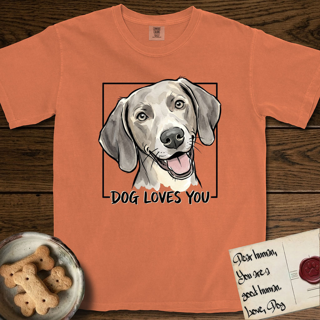 Dog Loves You Weimaraner T-Shirt flat lay in Melon, featuring Ink and watercolor portrait of a smiling silver grey Weimaraner with long velvet hanging ears and pale amber eyes, head tilted inside a black frame above hand-lettered text reading DOG LOVES YOU.