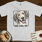 Dog Loves You Weimaraner T-Shirt flat lay in White, featuring Ink and watercolor portrait of a smiling silver grey Weimaraner with long velvet hanging ears and pale amber eyes, head tilted inside a black frame above hand-lettered text reading DOG LOVES YOU.