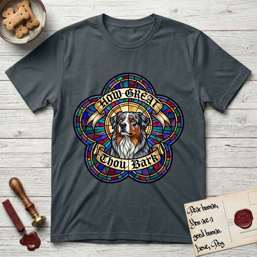 How Great Thou Bark Australian Shepherd T-Shirt flat lay in Dark Heather Grey, featuring a full-color stained-glass saint window of a blue merle Australian Shepherd with one blue eye and one amber eye, haloed in golden light.