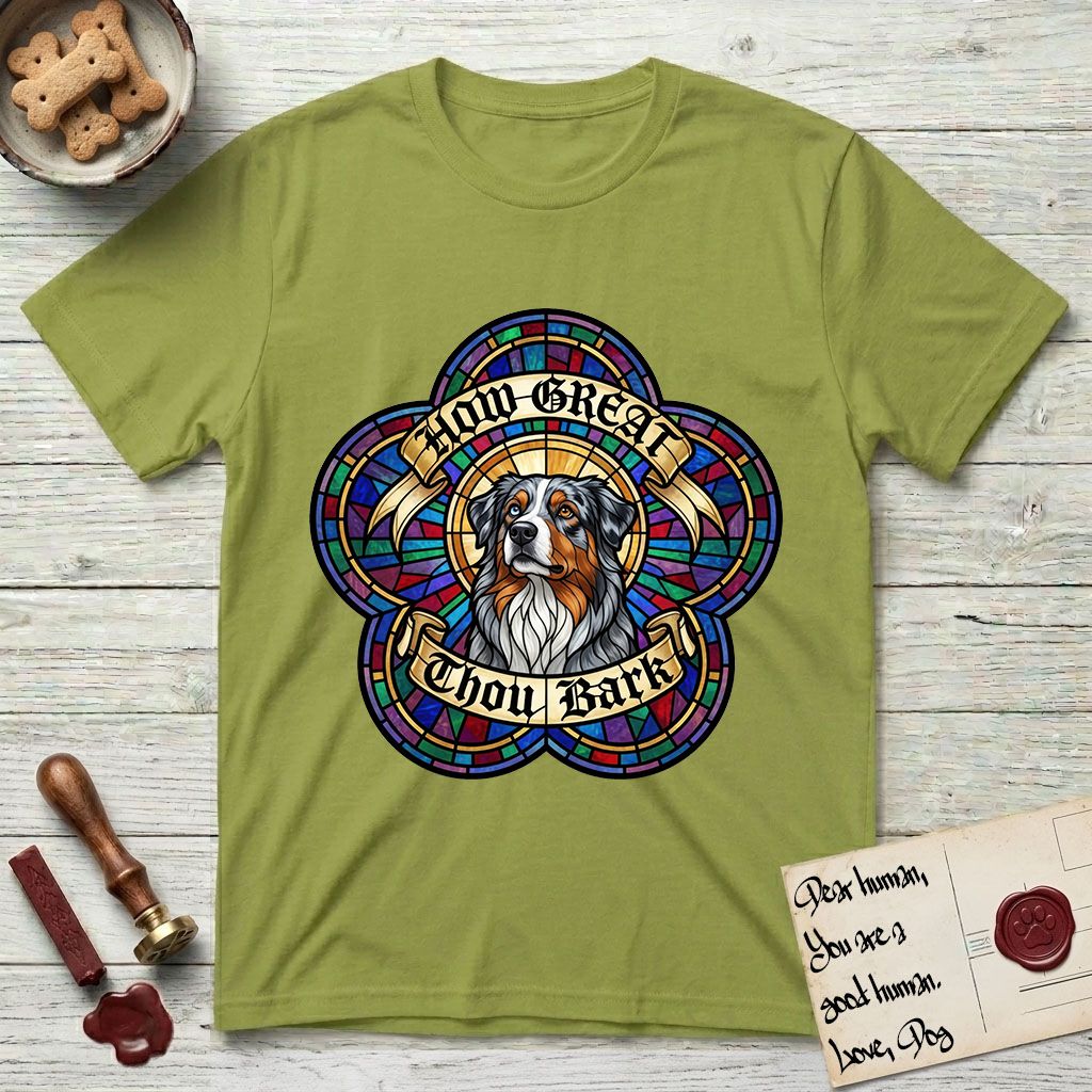 How Great Thou Bark Australian Shepherd T-Shirt flat lay in Kiwi, featuring a full-color stained-glass saint window of a blue merle Australian Shepherd with one blue eye and one amber eye, haloed in golden light.