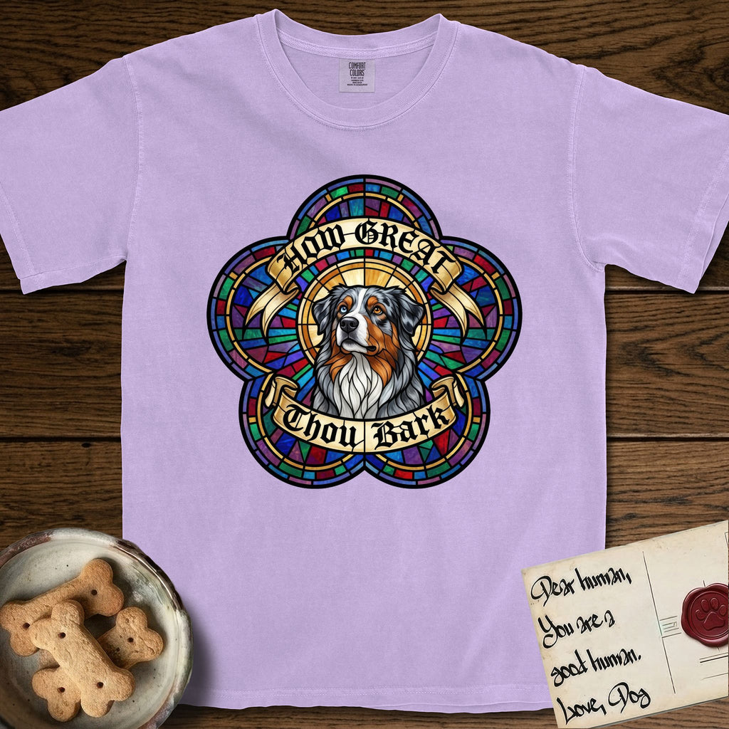 How Great Thou Bark Australian Shepherd T-Shirt flat lay in Orchid, featuring a full-color stained-glass saint window of a blue merle Australian Shepherd with one blue eye and one amber eye, haloed in golden light.